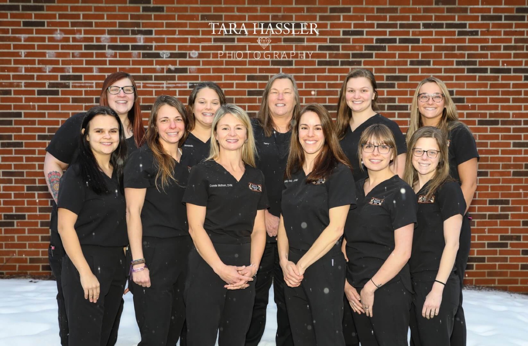 The full clinic team in black scrubs lined up against a red brick wall