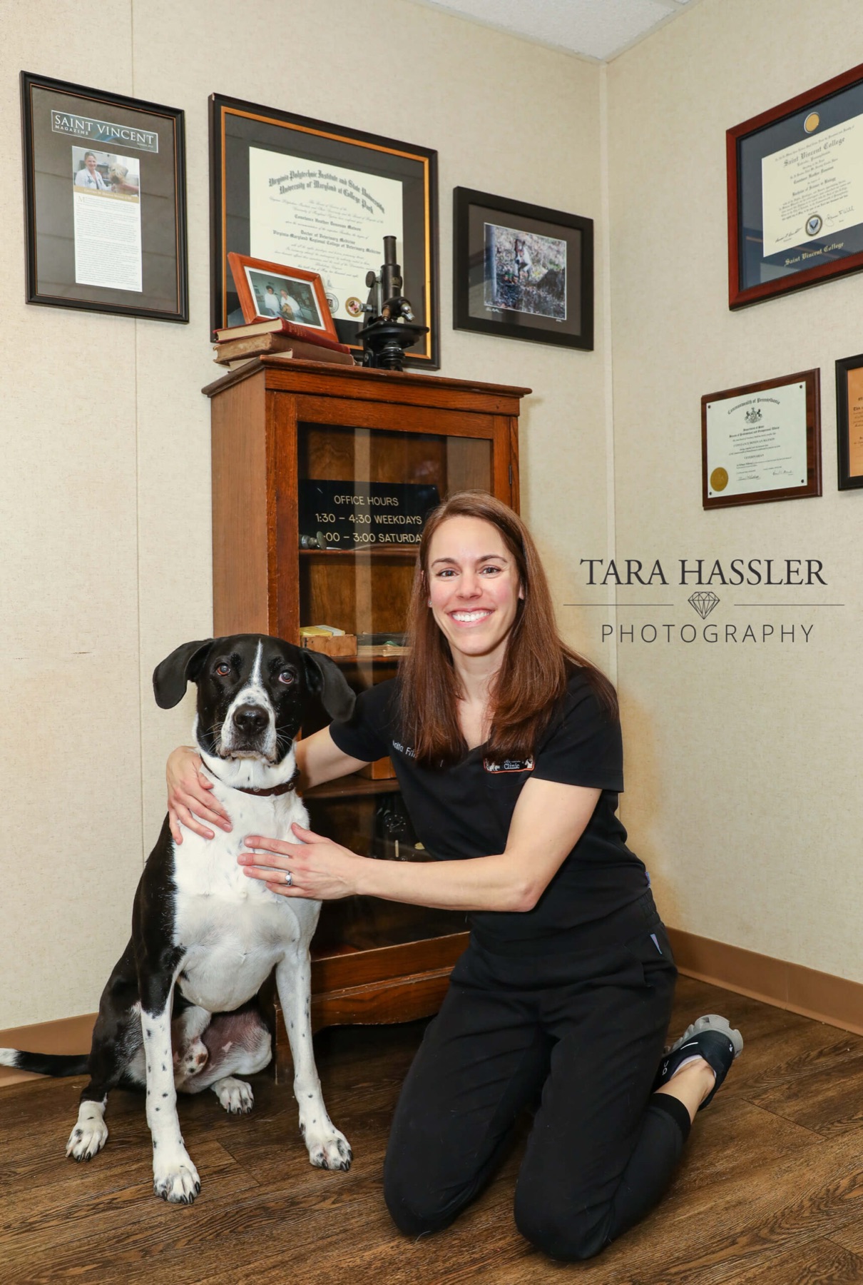 Dr. Anita Fritz kneeling with a black and white dog in the clinic office